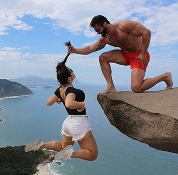 foto de um homem segurando uma mulher num penhasco